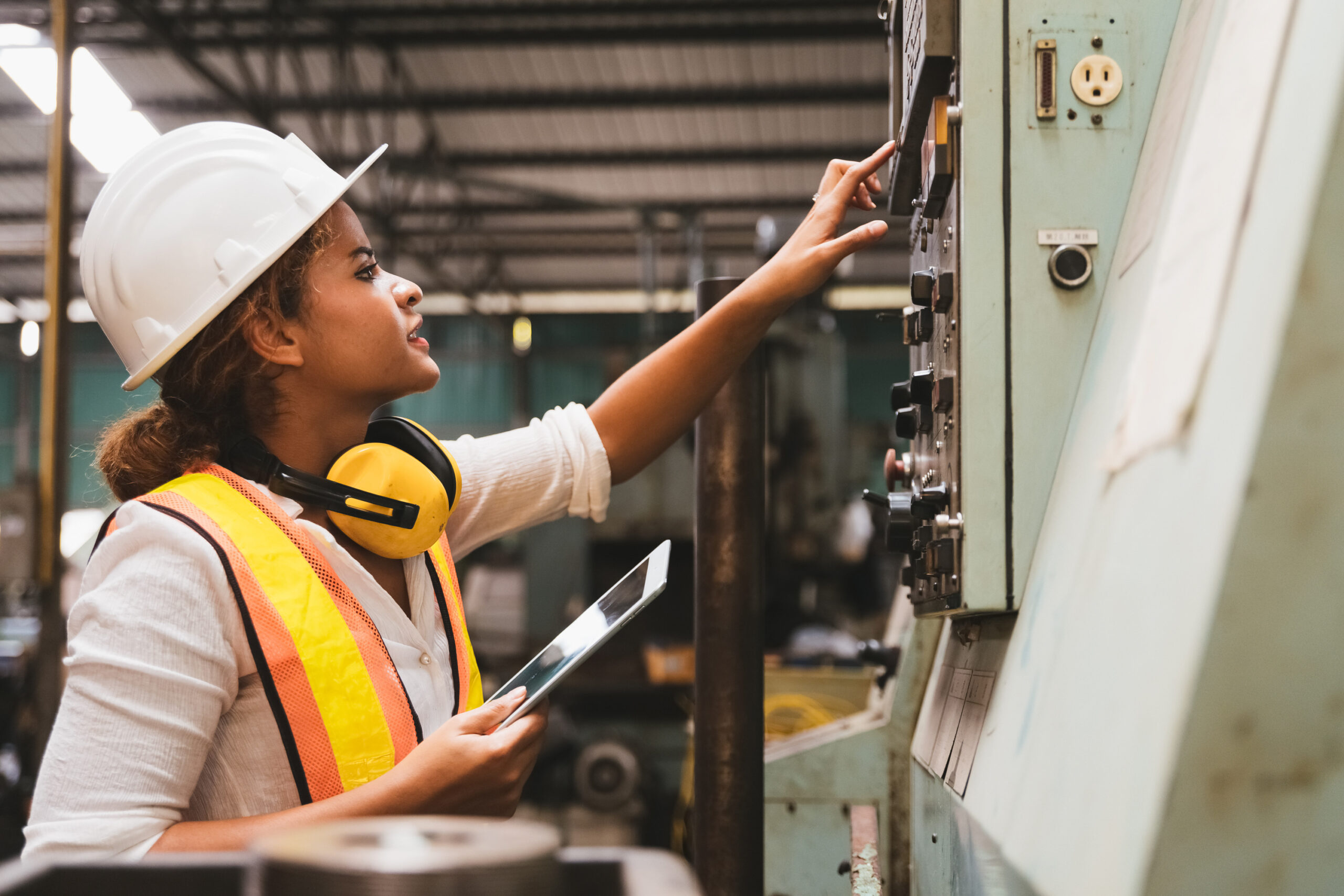En jente sjekker et elektrisk anlegg i et industrianlegg.