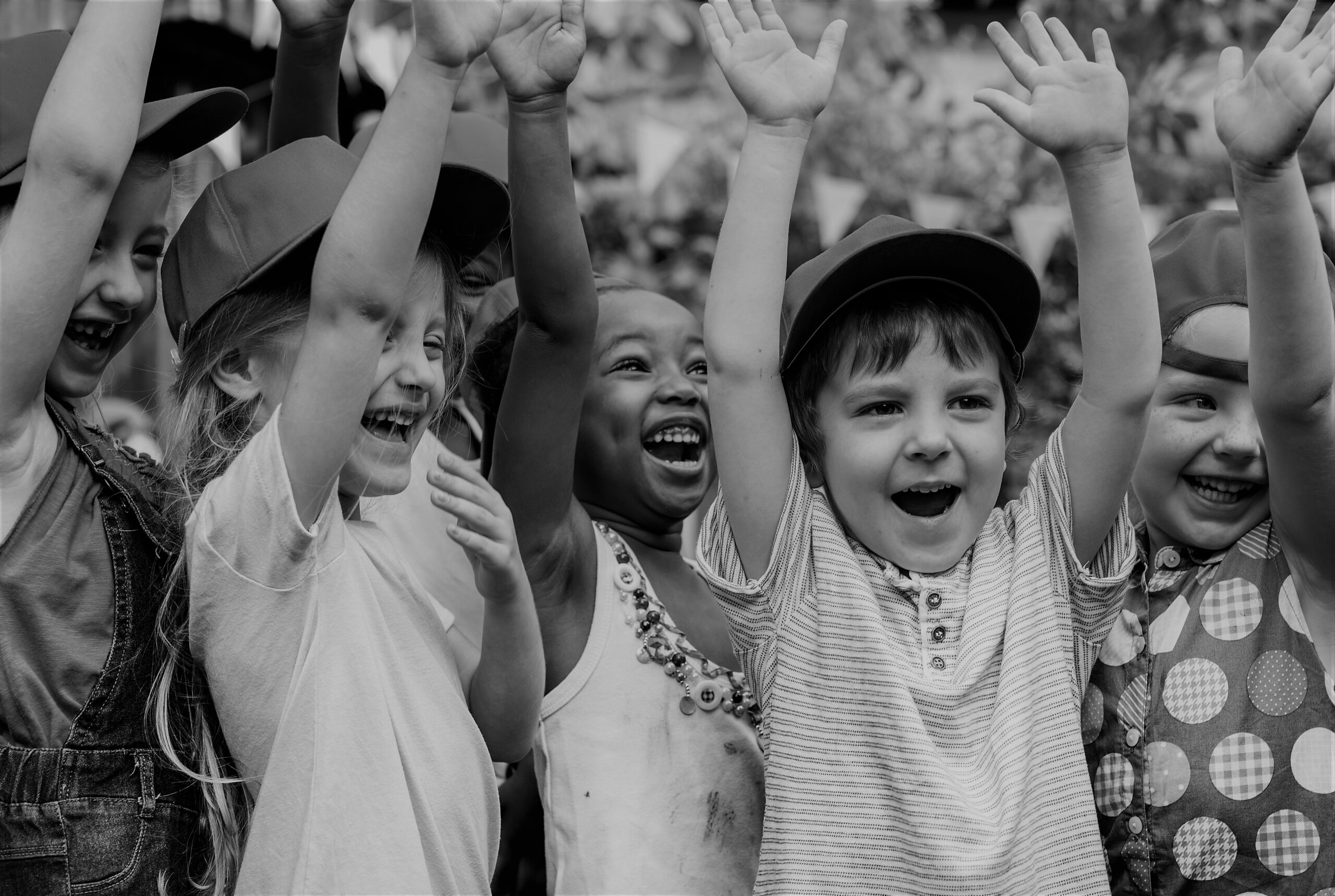 En gruppe smilende barn med hendene i været.