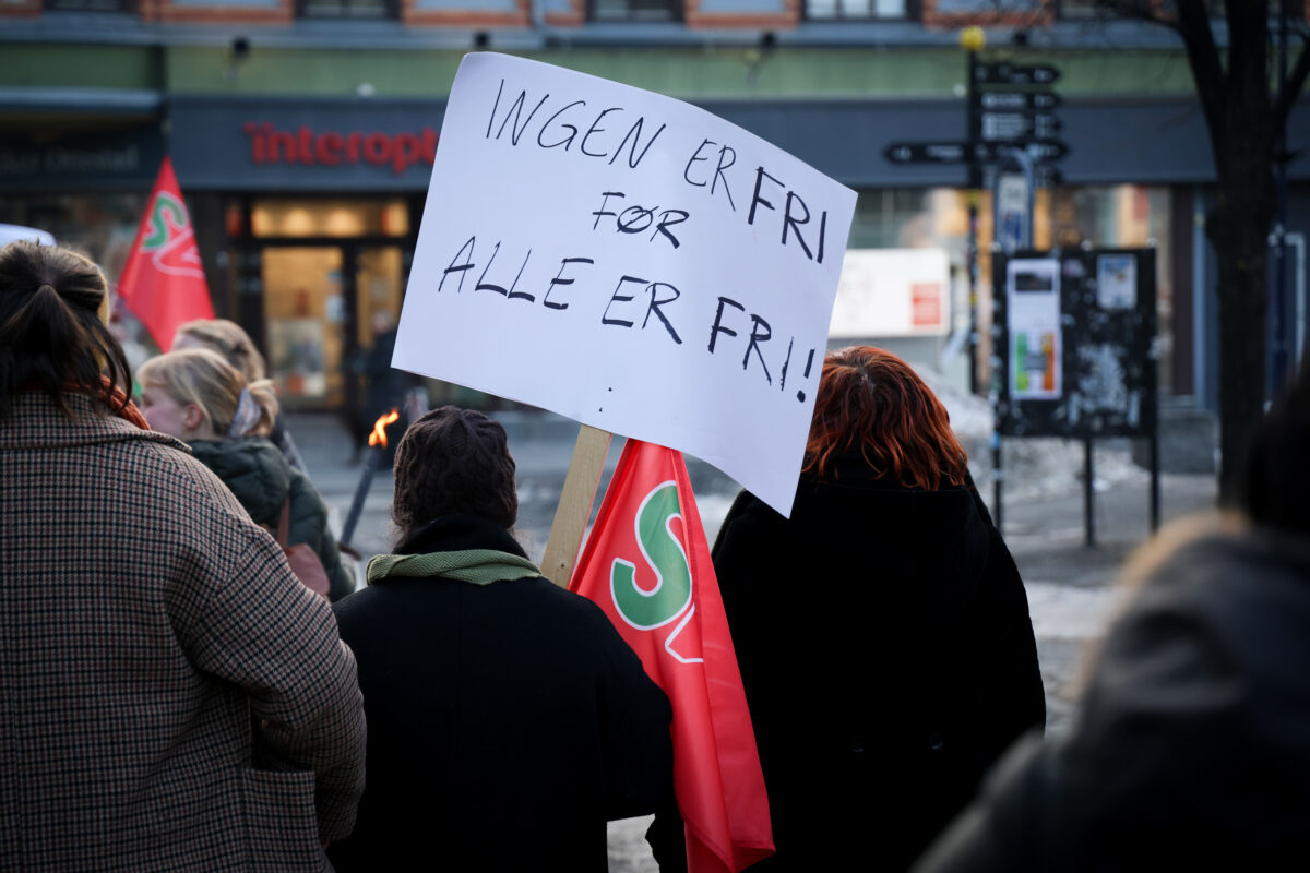 8. mars-tog. En person holder en plakat med teksten Ingen er fri, før alle er fri.