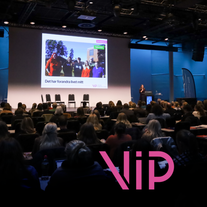 Forsamling foran en presentasjon av VIP. Bokstavene VIP står i rosa foran i bildet.