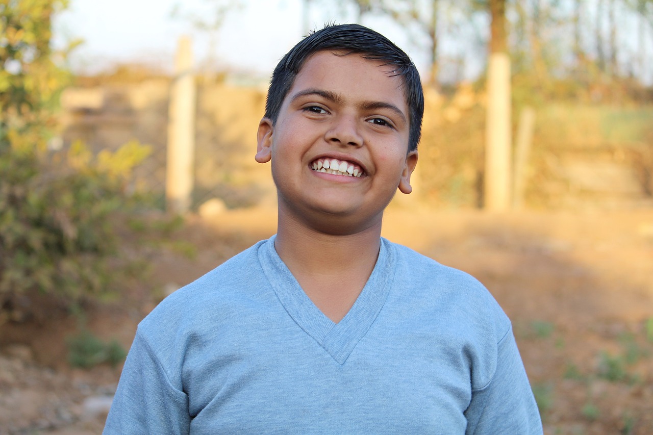 Ung gutt smiler mot kamera. Han har på blå genser.