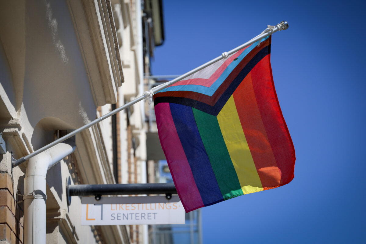 Det progressive pride-flagget henger foran skilt med Likestillingssenteret-logo.