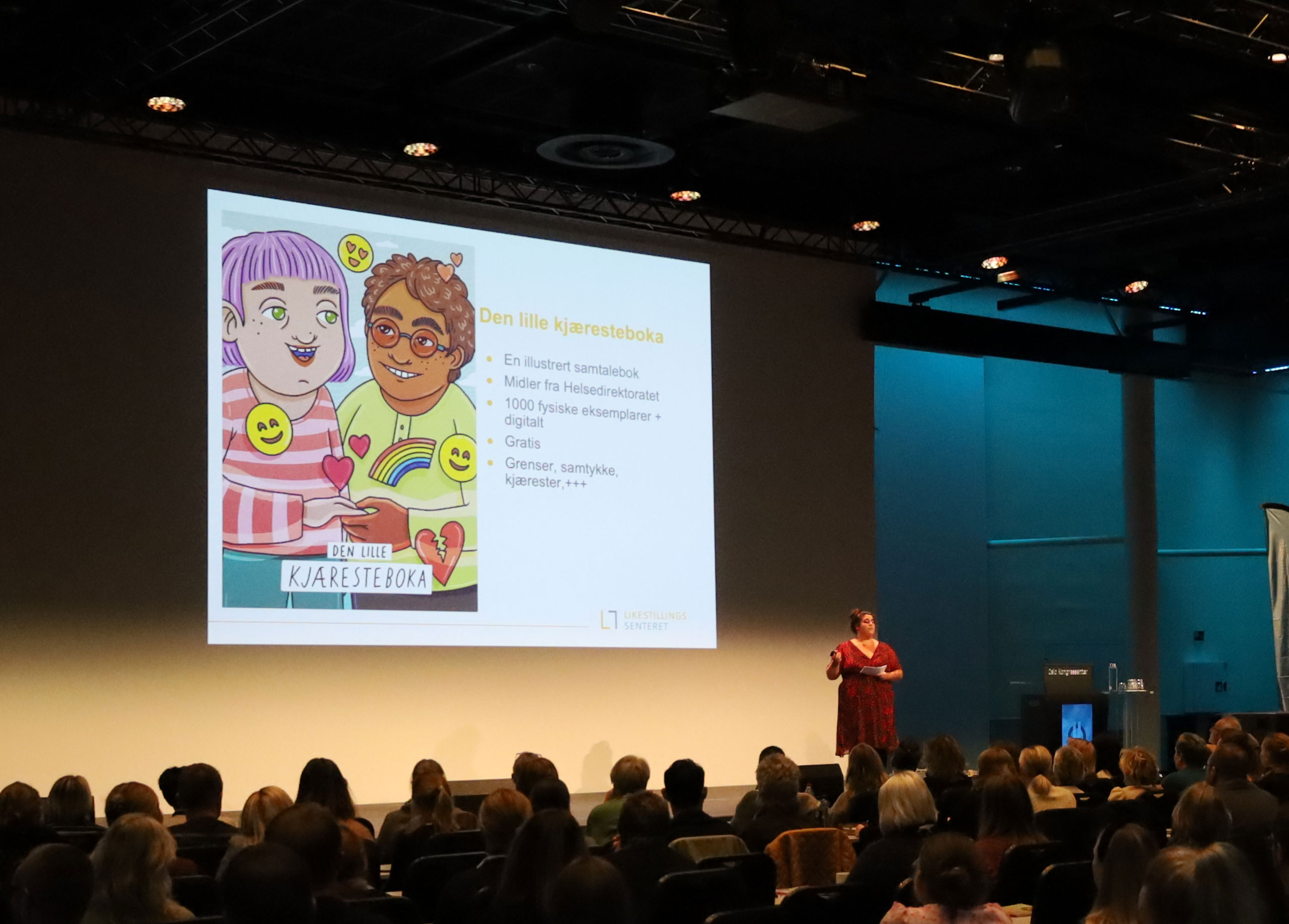 Carina Carlsen står på scenen foran et stort publikum.