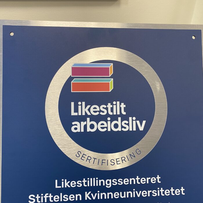 Logo til Likestilt Arbeidsliv står på mørkeblå bakgrunn. Et fargerikt er lik-tegn er plassert over teksten.