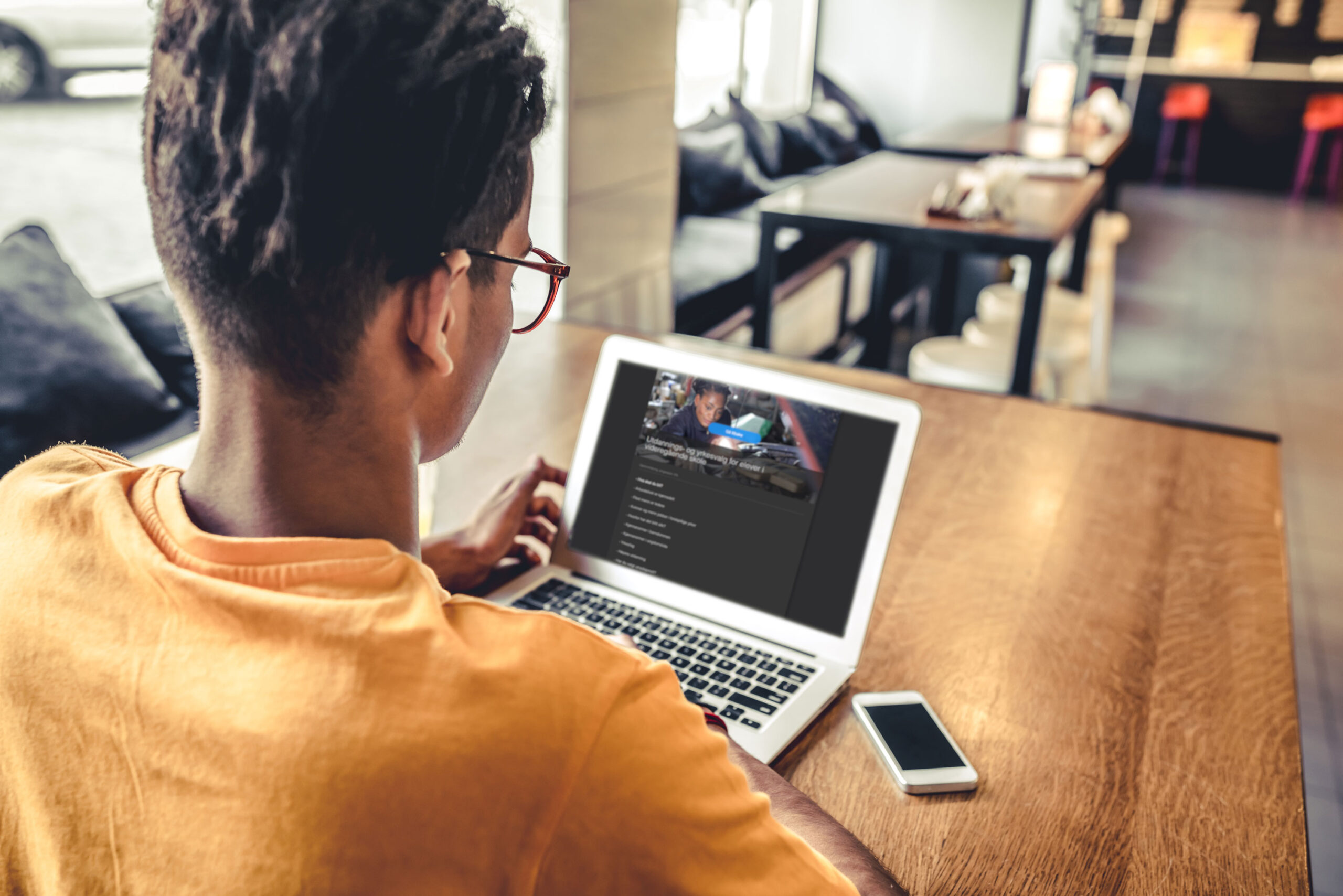 En person sett bakfra, sitter foran en laptop.