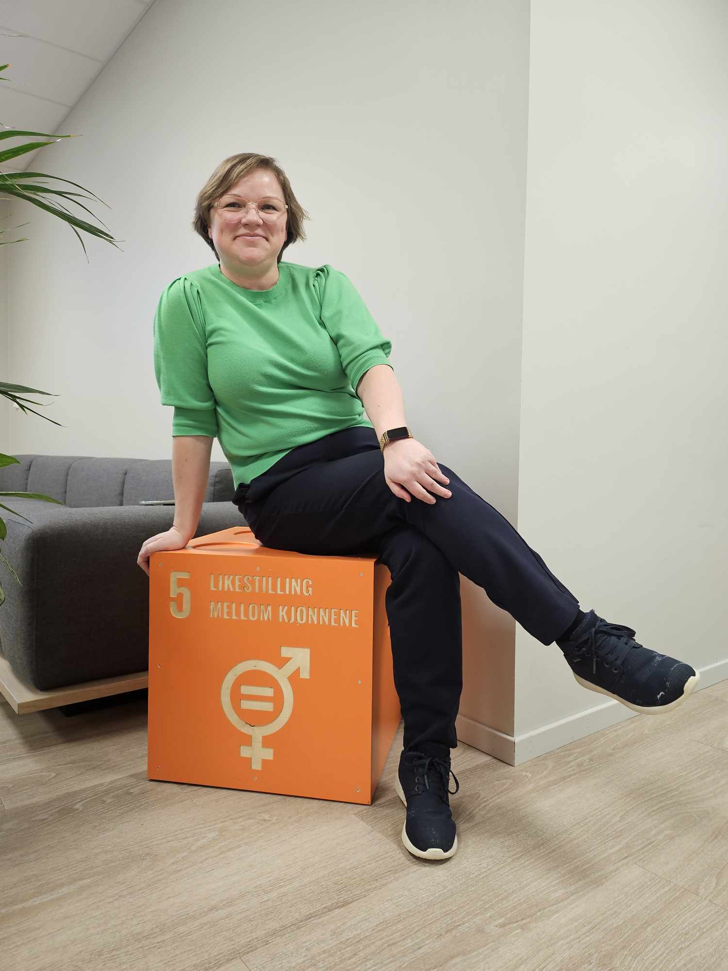 Annette Solberg sitter på en oransje boks med teksten likestilling mellom kjønnene skrevet på.