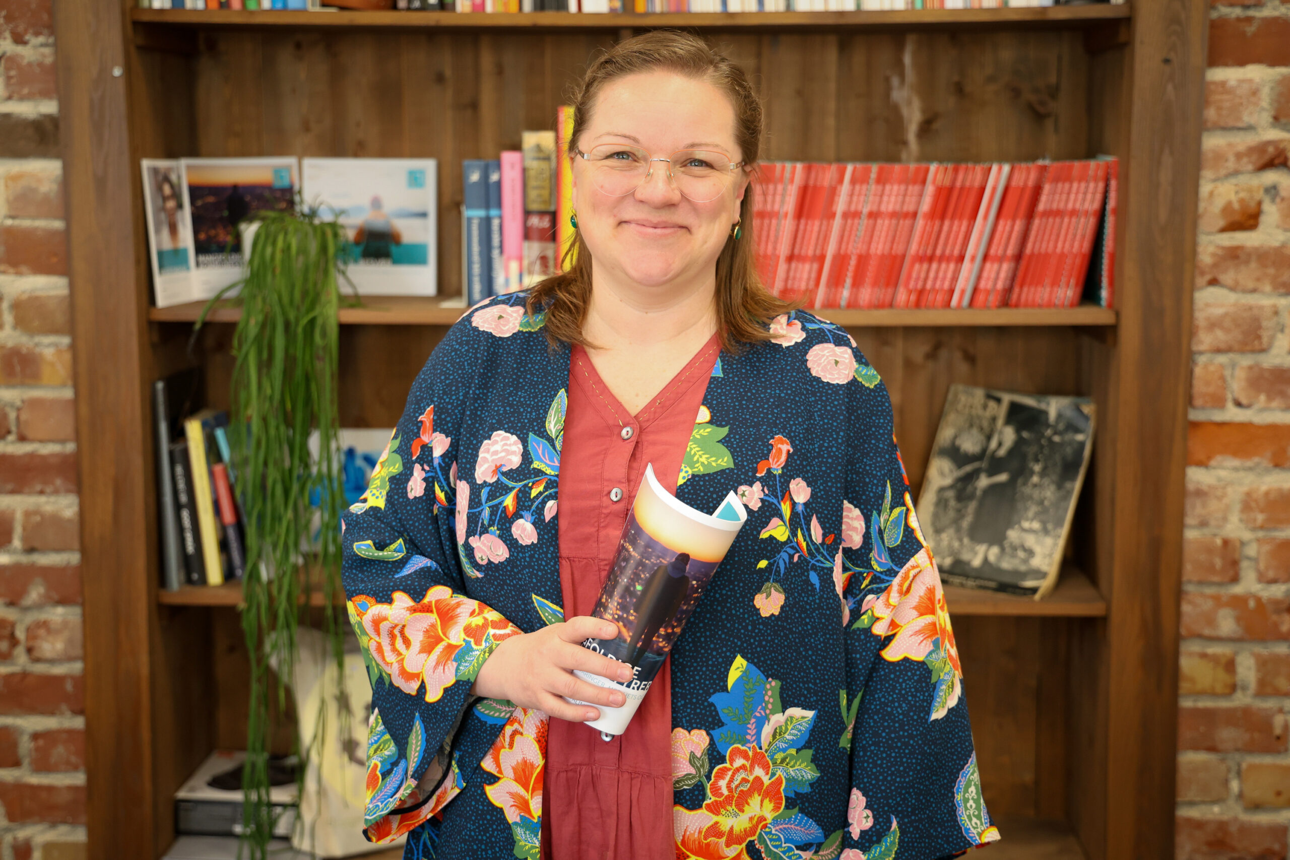 Annette Solberg står foran en bokhylle. Hun ser i kamera og smiler.