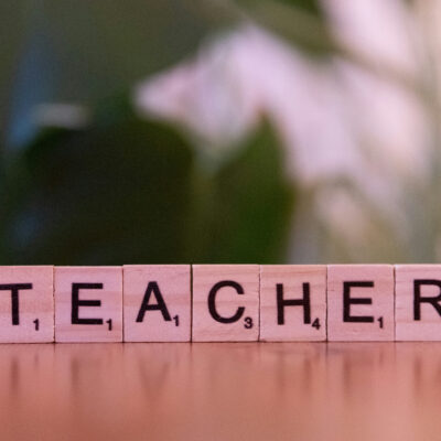 Ordet TEACHER stavet med klosser på et bord.