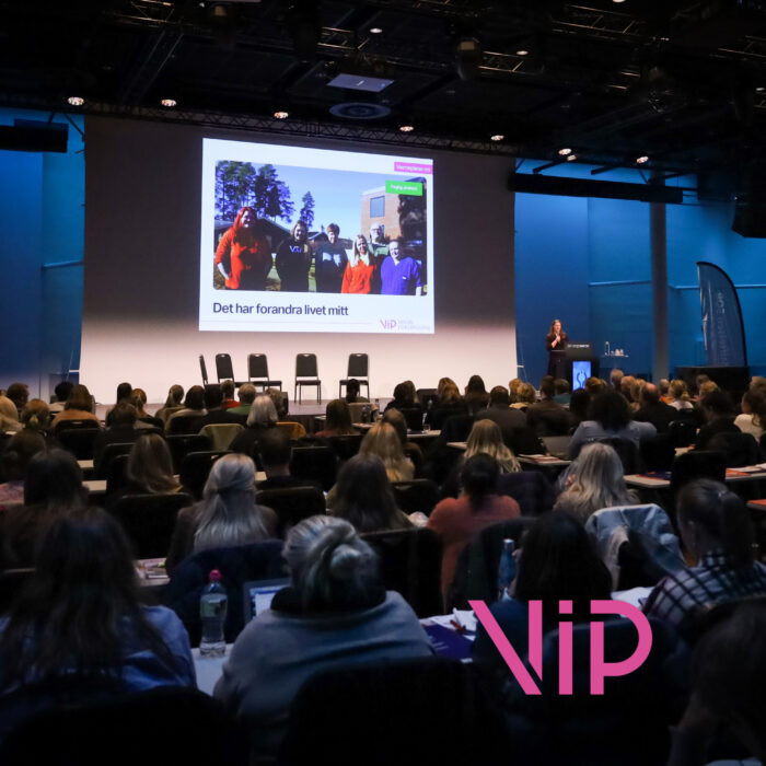 Publikum foran en storskjerm med bilde av en gjeng mennesker og teksten «Det har forandre livet mitt.»