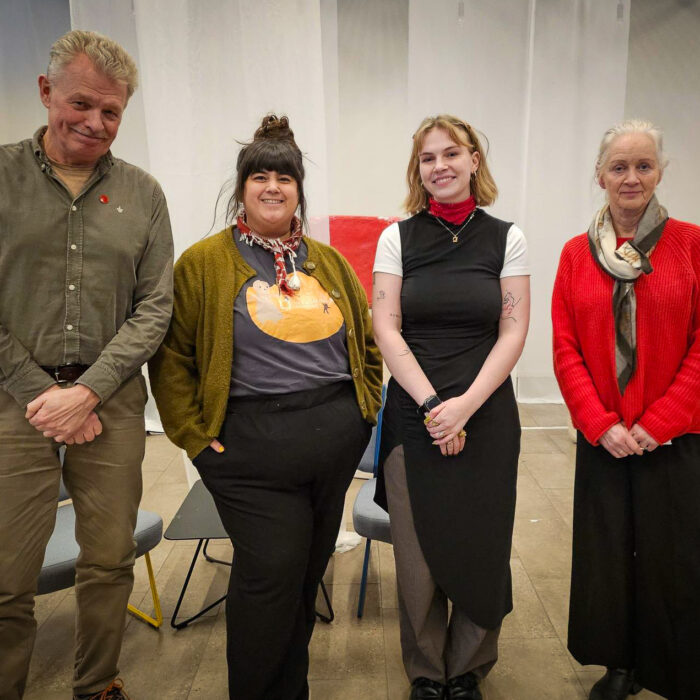 Fire personer på rekke, alle ser i kamera.