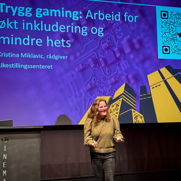 Kristina Miklavic på scenen for en presentasjon med teksten 'Trygg gaming: arbeid for økt inkludering og mindre hets'