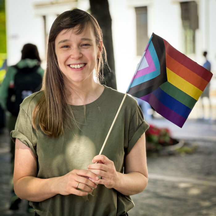 Silje Mathisen ser i kamera. Hun holde et prideflagg.